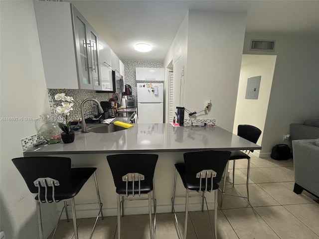 kitchen with kitchen peninsula, stainless steel range, white refrigerator, and a breakfast bar