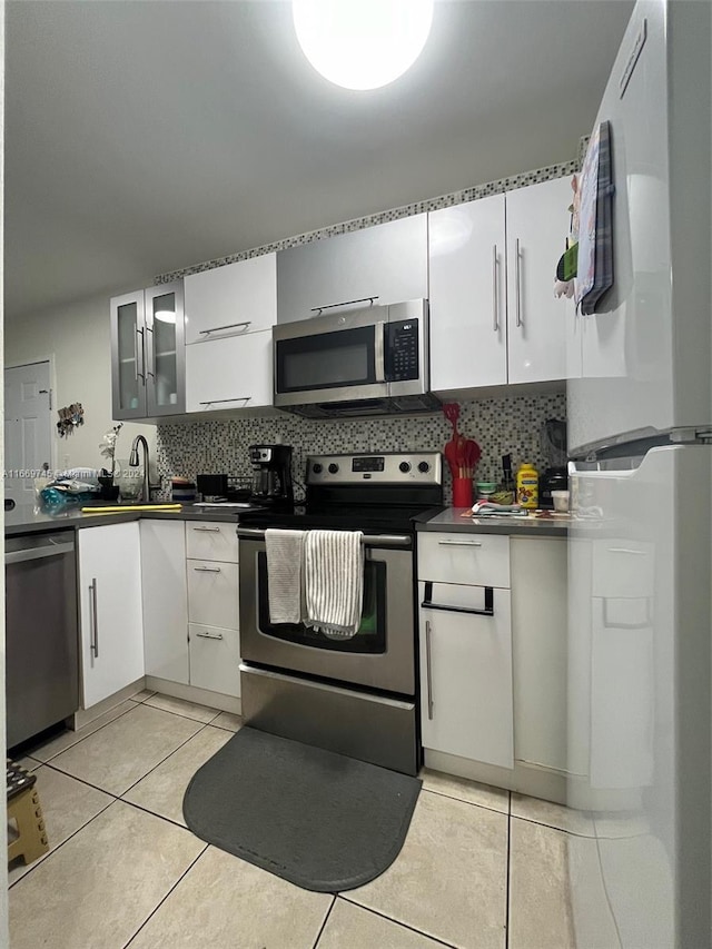 kitchen with appliances with stainless steel finishes, white cabinetry, sink, and backsplash