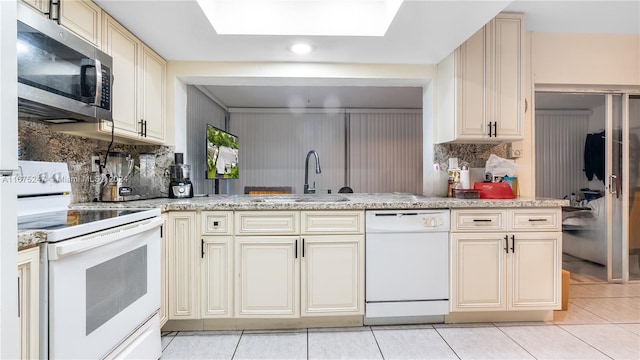 kitchen featuring white appliances, cream cabinets, backsplash, and kitchen peninsula