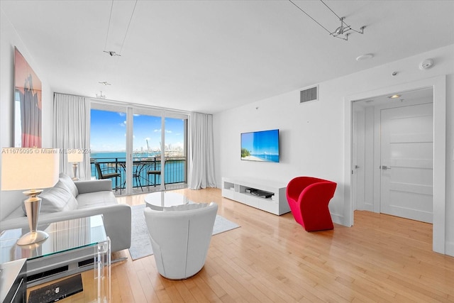 living room with a wall of windows and light hardwood / wood-style flooring