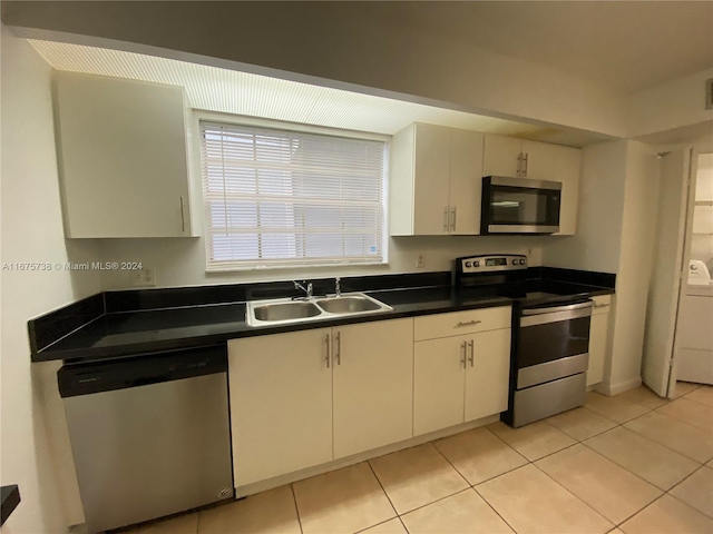 kitchen featuring appliances with stainless steel finishes, sink, light tile patterned floors, and white cabinets