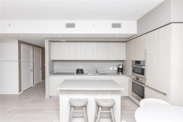 kitchen featuring a breakfast bar, a center island, light wood-type flooring, and sink