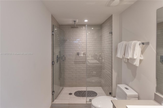 bathroom featuring a shower with door, vanity, and toilet