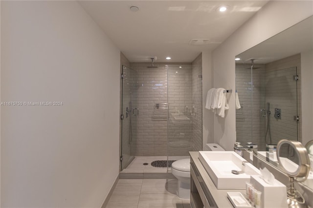 bathroom with a shower with door, vanity, toilet, and tile patterned floors