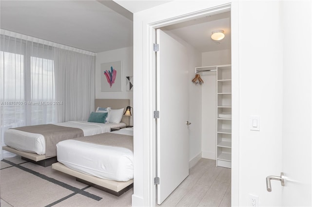 bedroom featuring a closet, light hardwood / wood-style floors, and a walk in closet