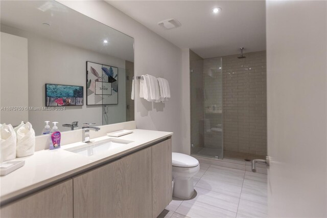 bathroom featuring a shower with door, vanity, toilet, and tile patterned flooring