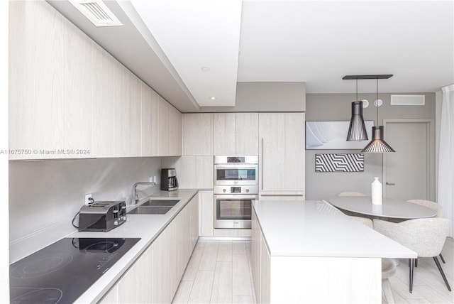 kitchen featuring double oven, black electric cooktop, sink, a center island, and pendant lighting