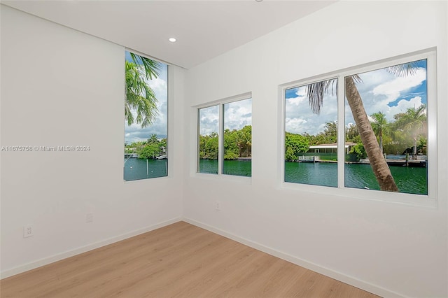 unfurnished room featuring a water view and wood-type flooring