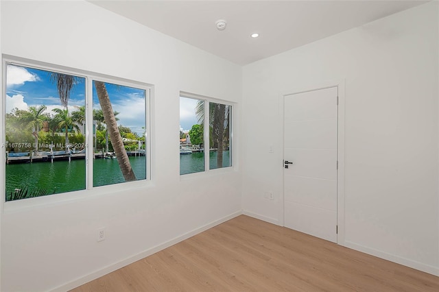 spare room featuring a water view and wood-type flooring