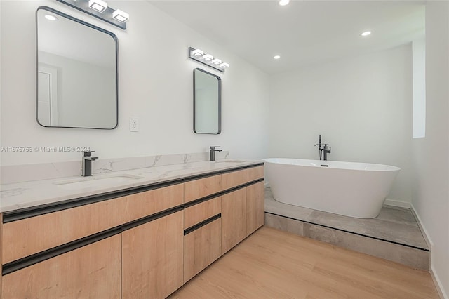 bathroom featuring hardwood / wood-style floors, a tub to relax in, and vanity