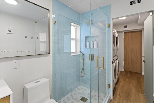 bathroom featuring an enclosed shower, toilet, stacked washer / drying machine, vanity, and hardwood / wood-style flooring