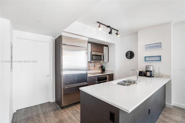 kitchen featuring sink, kitchen peninsula, stainless steel appliances, light hardwood / wood-style floors, and decorative backsplash