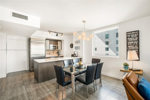 dining space featuring a notable chandelier, rail lighting, and sink