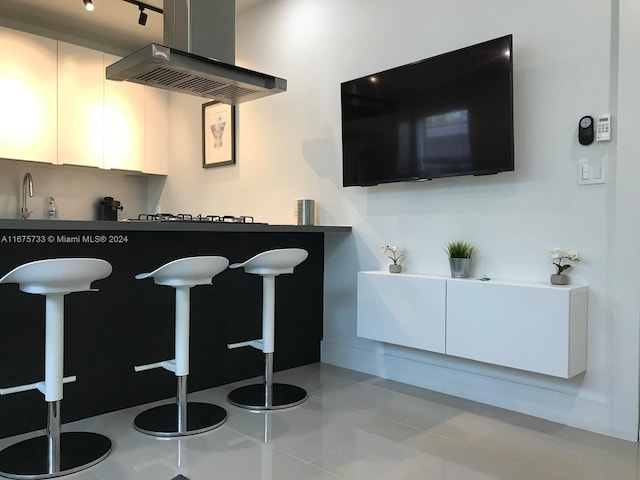 kitchen featuring white cabinetry, sink, gas stovetop, ventilation hood, and light tile patterned flooring