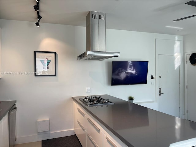 kitchen featuring white cabinets, stainless steel appliances, track lighting, and wall chimney exhaust hood