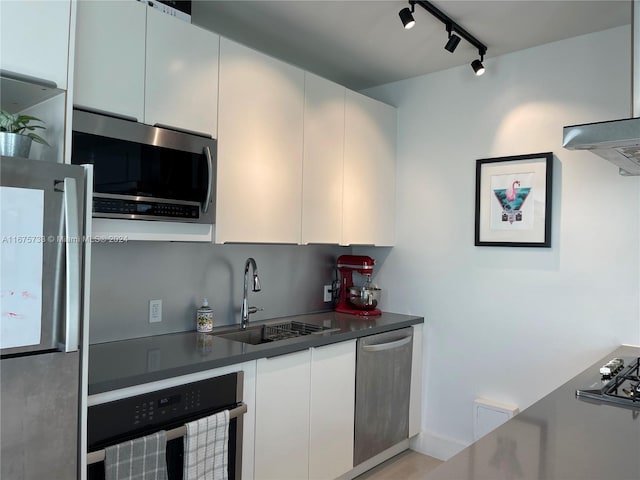 kitchen featuring white cabinets, rail lighting, stainless steel appliances, and sink