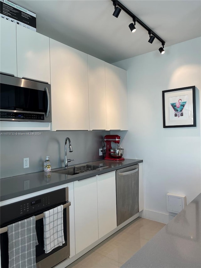 kitchen with white cabinetry, sink, rail lighting, and appliances with stainless steel finishes