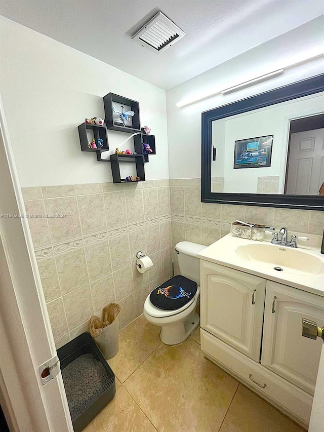 bathroom featuring tile patterned flooring, tile walls, vanity, and toilet