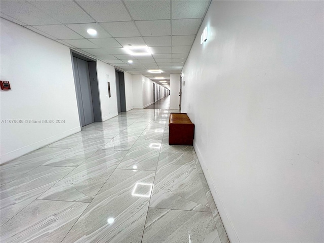 hall featuring a paneled ceiling and elevator