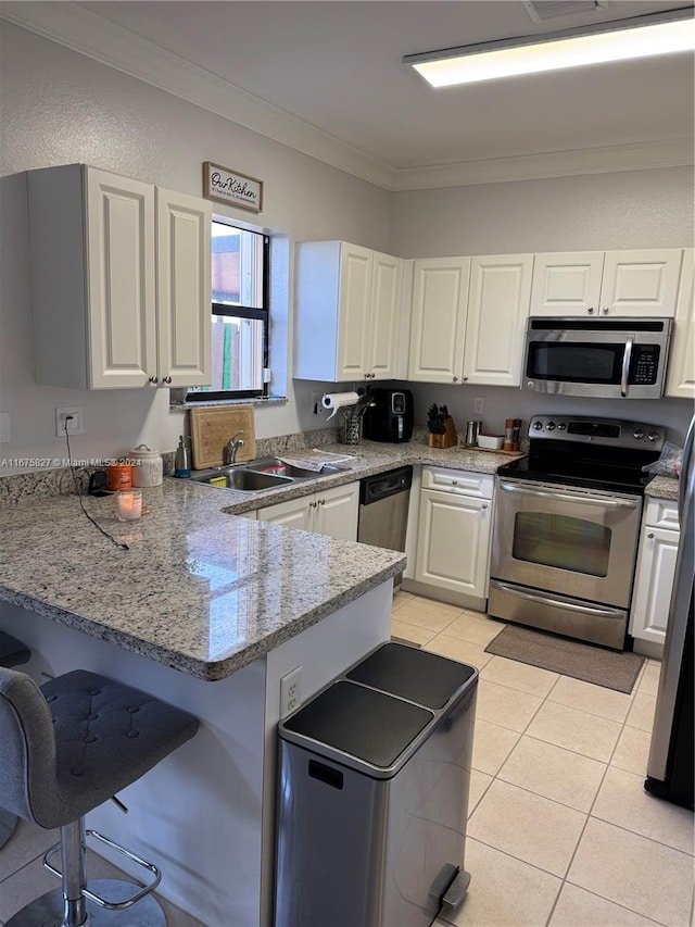 kitchen featuring kitchen peninsula, white cabinetry, ornamental molding, sink, and stainless steel appliances