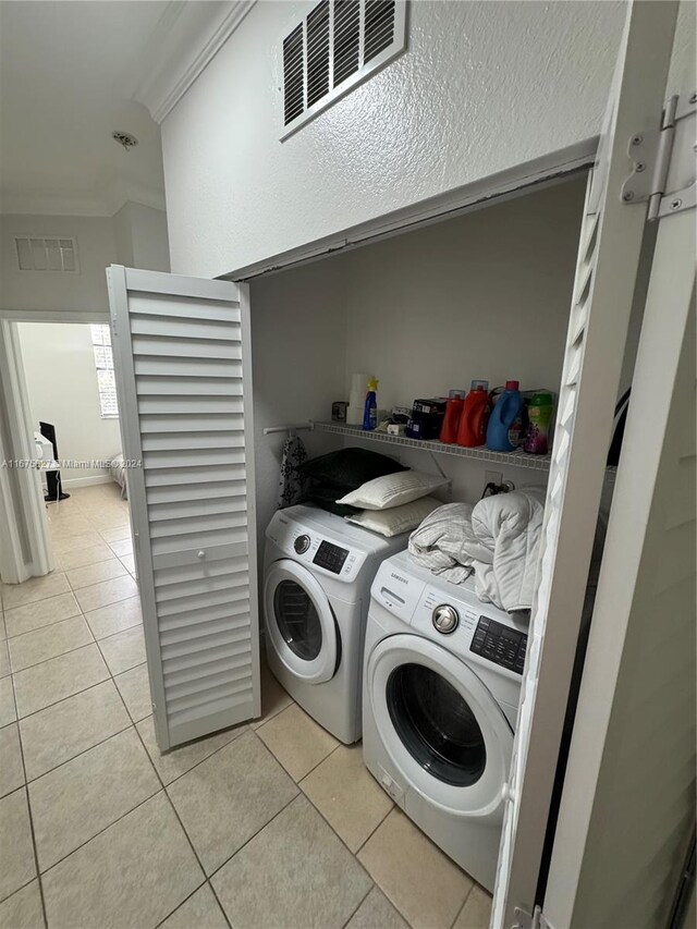 laundry room featuring independent washer and dryer, ornamental molding, and light tile patterned flooring