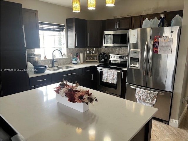 kitchen featuring decorative backsplash, hanging light fixtures, sink, and stainless steel appliances