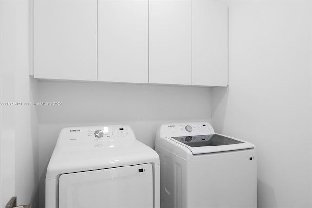 clothes washing area with cabinets and separate washer and dryer