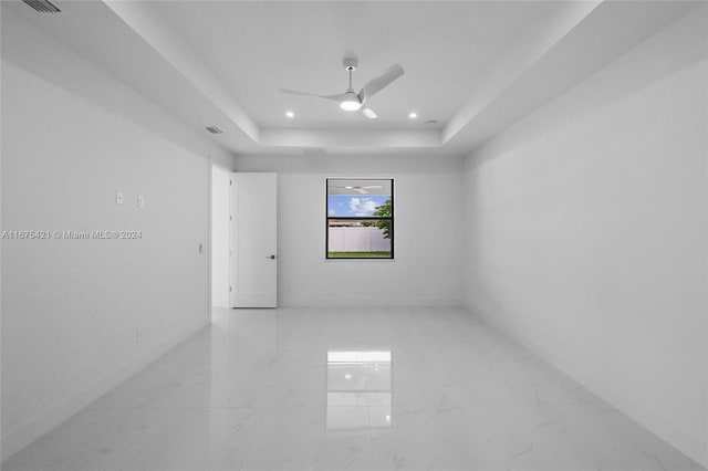 empty room with a tray ceiling and ceiling fan