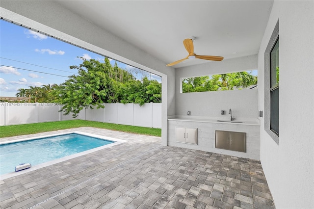 view of pool with exterior kitchen, a patio, and ceiling fan