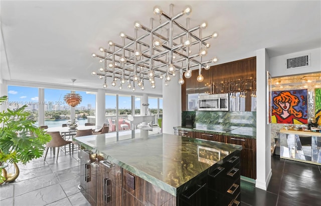 kitchen with a water view, dark brown cabinetry, decorative backsplash, and a center island