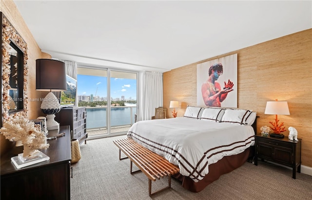 bedroom featuring a water view, access to outside, and carpet