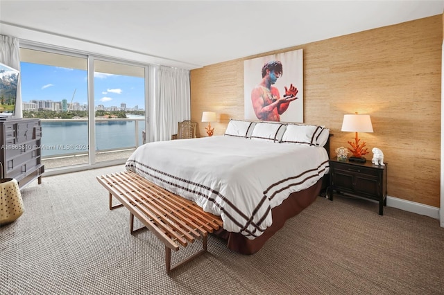 carpeted bedroom with access to outside, wooden walls, and a water view