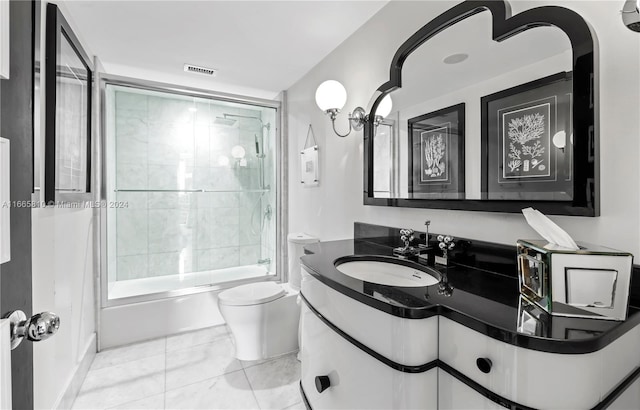 full bathroom featuring bath / shower combo with glass door, vanity, tile patterned flooring, and toilet