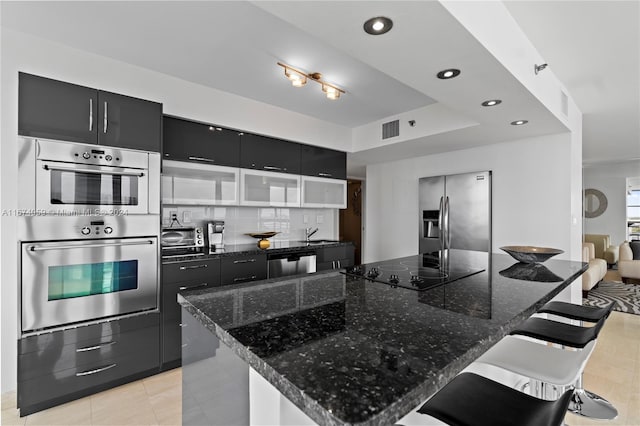 kitchen with appliances with stainless steel finishes, backsplash, a kitchen island, and a kitchen breakfast bar