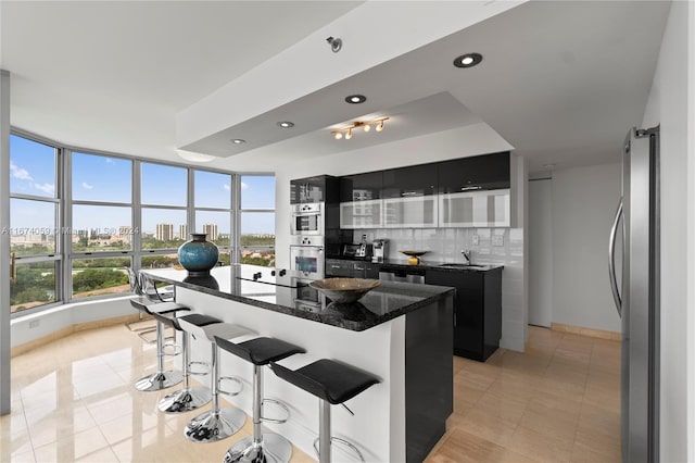 kitchen with decorative backsplash, a kitchen breakfast bar, stainless steel appliances, sink, and a center island