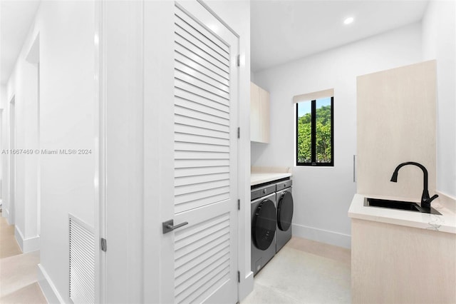 laundry area featuring independent washer and dryer, sink, and cabinets