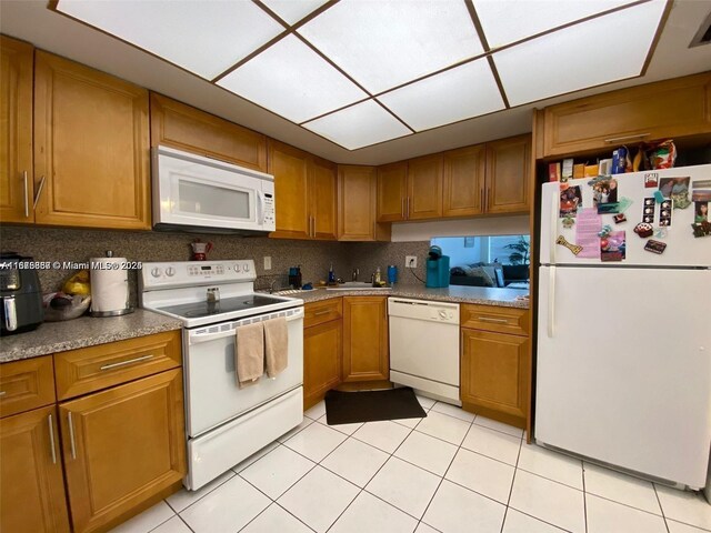 kitchen with light tile patterned floors, white appliances, and backsplash