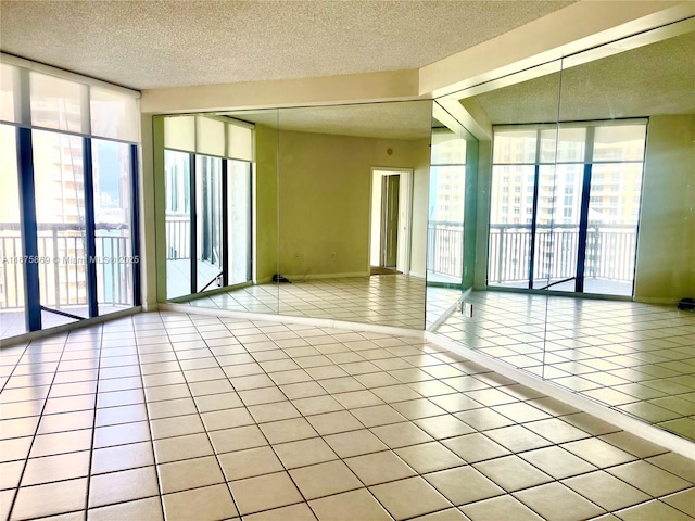 spare room featuring a wall of windows, light tile patterned floors, and a textured ceiling