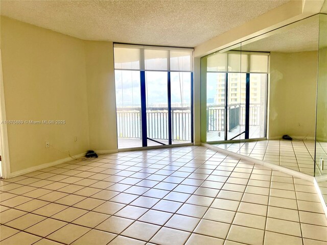 tiled empty room featuring a textured ceiling and floor to ceiling windows