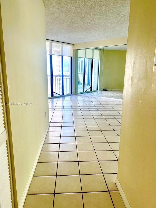 tiled empty room with a textured ceiling and expansive windows