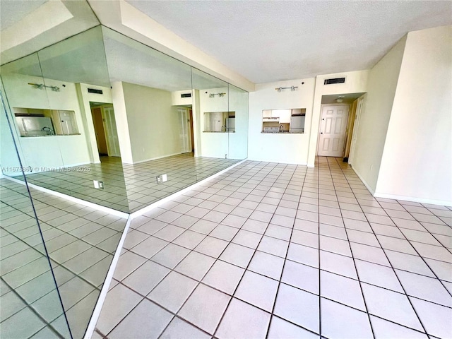 unfurnished living room featuring light tile patterned floors and a textured ceiling