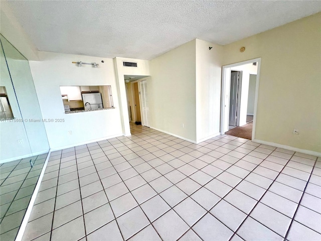 empty room with light tile patterned flooring and a textured ceiling