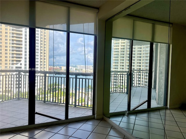 doorway to outside featuring a wall of windows, a water view, and tile patterned flooring