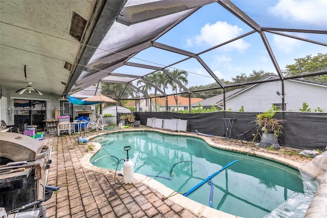 view of pool featuring grilling area, a patio, glass enclosure, and ceiling fan