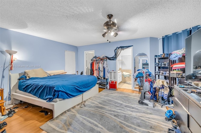 bedroom with ensuite bathroom, hardwood / wood-style flooring, a textured ceiling, and ceiling fan