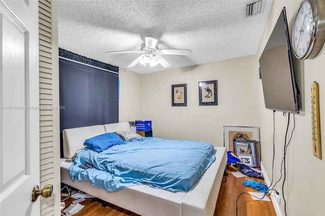 bedroom featuring ceiling fan, wood-type flooring, and a textured ceiling