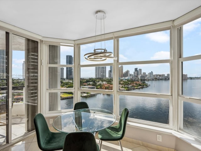 sunroom / solarium featuring an inviting chandelier and a water view