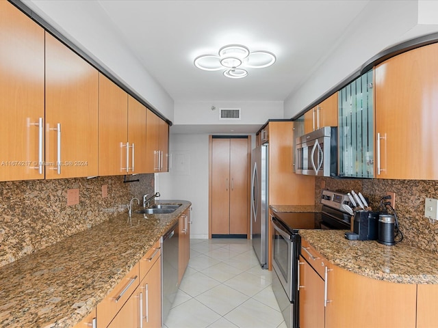 kitchen with decorative backsplash, stainless steel appliances, sink, stone countertops, and light tile patterned floors