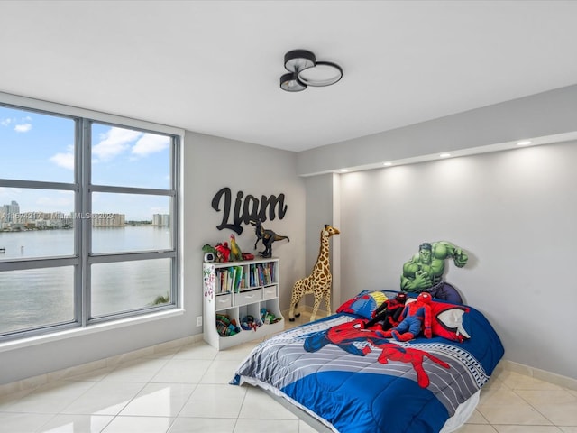 bedroom featuring light tile patterned flooring, a water view, and multiple windows