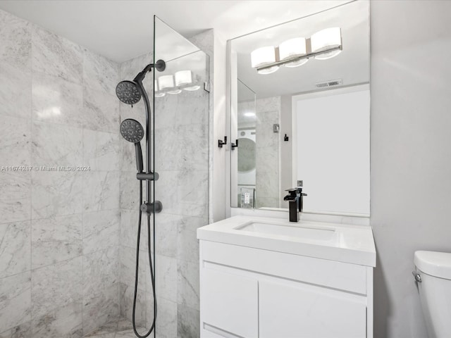 bathroom with a tile shower, toilet, and vanity